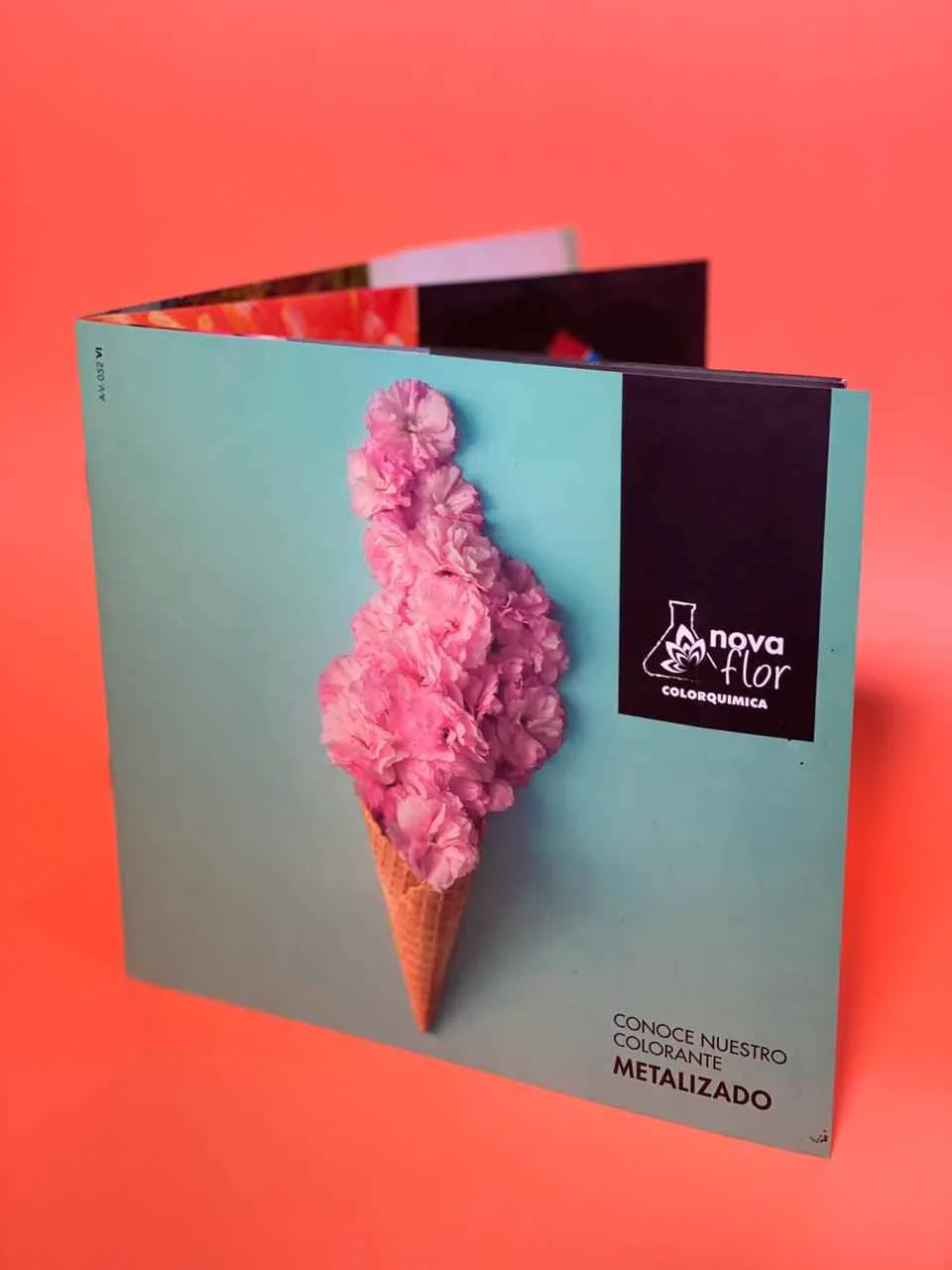 Brochure plegado con portada turquesa sobre fondo coral