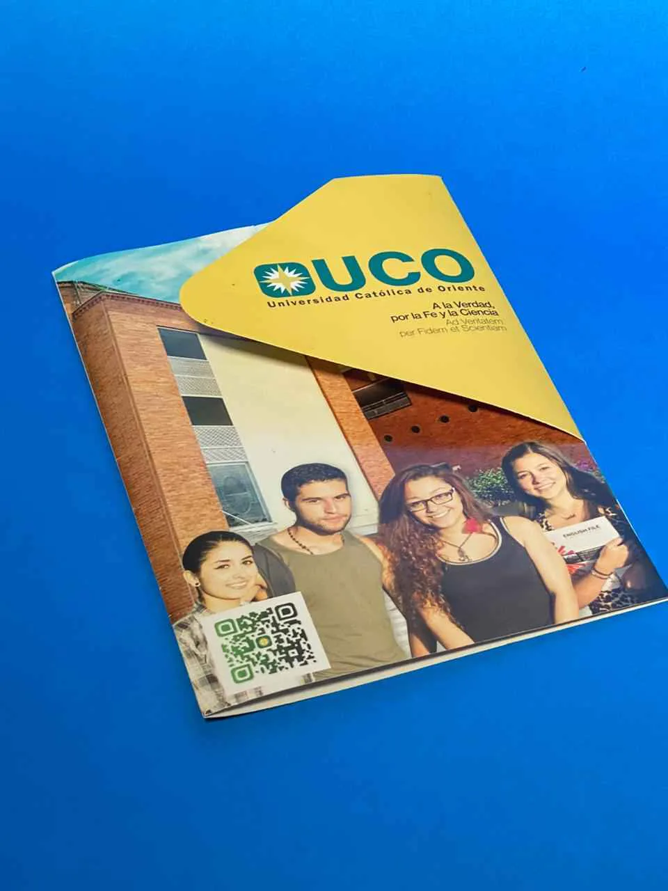 Carpeta institucional impresa con fotografía, fondo azul y solapa diagonal amarilla