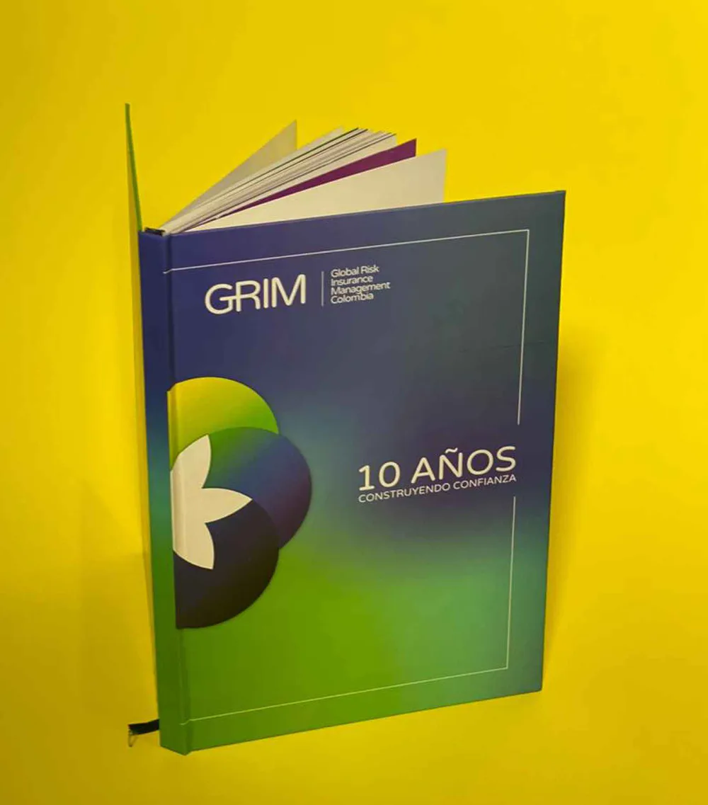 Libro corporativo de cubierta rígida azul y verde abierto sobre un fondo amarillo